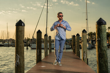 Fashion business man near the yacht. Portrait of fashion model outdoor. Fashion male posing near...