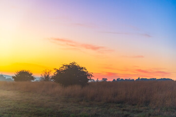 Sunrise over the countryside on the outskirts of country town with high cloud