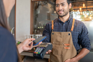 Happy Owner recieve scan QR code to pay in cafe restaurant with a digital payment without cash....