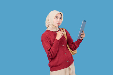A woman in a red sweater is holding a pen and looking at a tablet. She is deep in thought, possibly...