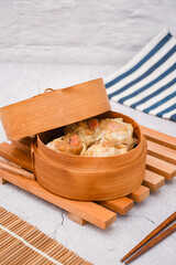Fresh dimsum siu mai in a bamboo steamer, served with chopsticks. Authentic Asian cuisine with soft dumpling skin and juicy meat filling. Perfect for food, restaurant, and culinary themes	