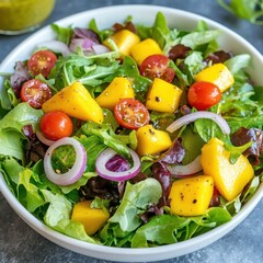 A healthy garden salad with mixed greens, cherry tomatoes, red onions, and mango.