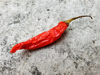 Dried red chili pepper isolated on grey concrete floor.