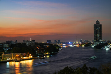 Fototapeta premium View of Bangkok, Thailand at night, showing the Chao Phraya River and boats. Taken on 22 Dec 2023.