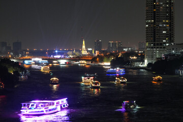 View of Bangkok, Thailand at night, showing the Chao Phraya River and boats. Taken on 22 Dec 2023.