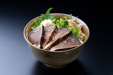 黒背景にたっぷり薬味を添えたカツオのたたき丼