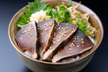 黒背景にたっぷり薬味を添えたカツオのたたき丼