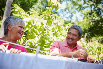 Hanging, laundry and smile with senior couple in garden of home together for chores or cleaning. Clothing, housework or washing line with happy mature man and woman outdoor in backyard for retirement