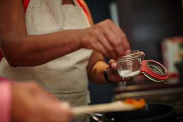 Hands, cooking and people in kitchen, salt and ingredients for food in small business, closeup or catering. Startup, entrepreneur and seasoning for meal prep, chef or cuisine for dinner in restaurant
