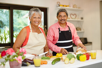 Cooking, portrait and smile of old couple in kitchen of home for retirement diet, health or nutrition. Ingredients, recipe or vegetables with happy senior man and woman in apartment for food or meal