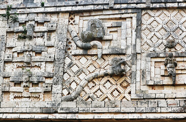 Close up of the Puuc stye frieze with carvings of serpents and chaac masks on the façade of the...