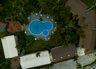 A pool is surrounded by palm trees and buildings