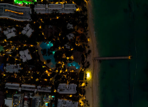 A nighttime aerial view of a beach with a city in the background