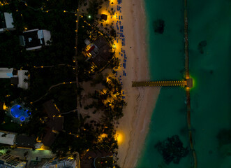 A nighttime aerial view of a beach with a pier and a hotel
