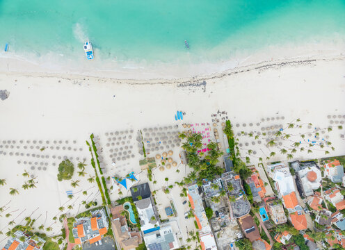 A beach with a lot of umbrellas and a house in the background