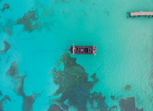 A boat is floating in the ocean with a dock in the background