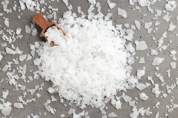 Plakat Top view of magnesium flakes scattered from scoop. Natural sea salt as wellness or spa products for bath or relaxation, self-care or sustainable living, Wellness and Body Function Enhancement