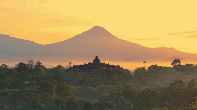 Aerial drone scene breathtaking of the ancient ruins of Borobudur Temple in sunrise time and mountain background, a 9th-century Mahayana Buddhist temple in Magelang, Central Java, Indonesia.