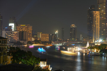 View of Bangkok, Thailand at night, showing the Chao Phraya River and boats. Taken on 22 Dec 2023.