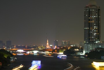 Fototapeta premium View of Bangkok, Thailand at night, showing the Chao Phraya River and boats. Taken on 22 Dec 2023.