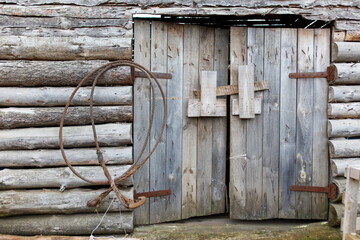 A wooden door with a rusty chain hanging from it