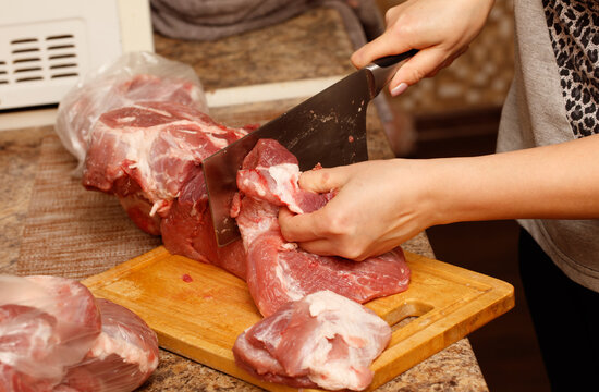 A woman is cutting meat on a cutting board