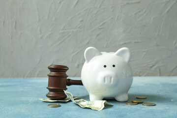 Piggy bank with judge gavel and money on grunge blue background. Concept of bankruptcy