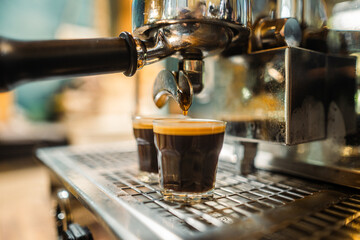 A barista crafts a hot beverage by pouring  espresso from a steel machine