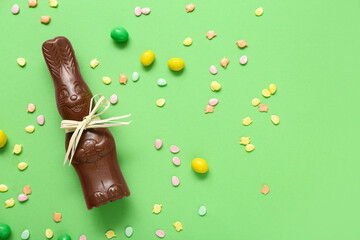 Chocolate Easter bunny with sprinkles and candies on green background