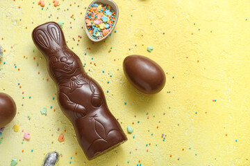 Chocolate Easter eggs with sprinkles and bunny on yellow background