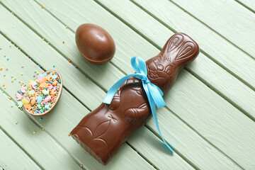 Chocolate Easter eggs with sprinkles and bunny on green wooden background