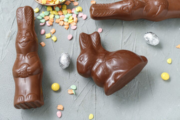Chocolate bunnies, Easter eggs in foil and sprinkles on grey background