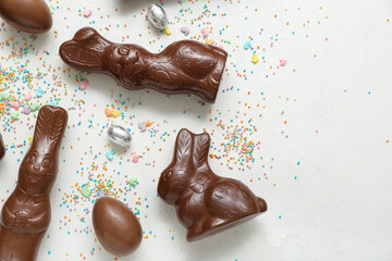 Chocolate Easter eggs with sprinkles and bunnies on white background