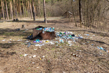 Overflowing garbage bin with litter in forest