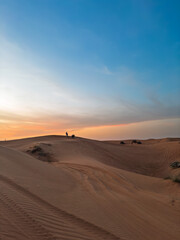 This breathtaking landscape captures the dramatic contrast between rugged rock formations and smooth red sand dunes in the UAE. A limestone ridge cuts through vibrant orange-red desert sands, with spa