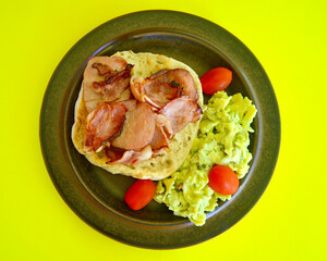A top view of grilled bacon on toasted Turkish bread with avocado pasta salad and cherry tomatoes.