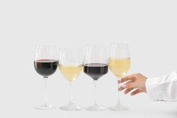 Female hand with glasses different exquisite wine on light background