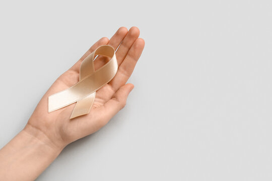 Woman with beige ribbon on light background. Uterine cancer awareness concept
