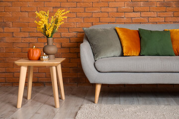 Interior of living room with grey sofa, cushions and pumpkins on coffee table