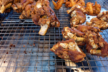 Crispy Fried Pork Knuckles - Thai Street Food Delight. The golden-brown crust, crunchy texture, deep-fried pork knuckles freshly prepared and displayed on a wire rack at a Thai street food market.
