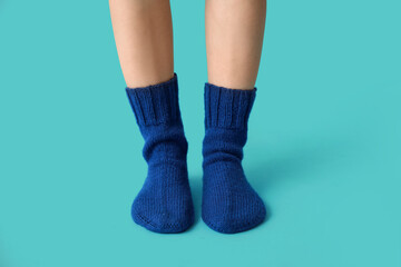 Legs of young woman in warm knitted socks on blue background