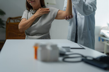 Doctor examining senior woman's arm for arthritis in medical office