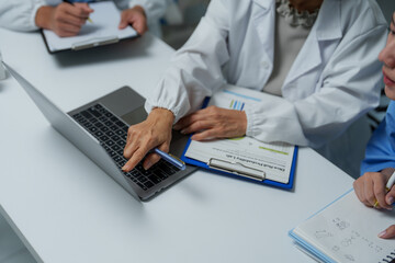 Medical researchers analyzing data on laptop and documents in laboratory