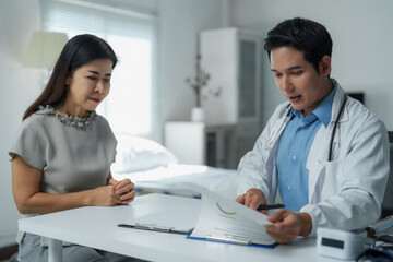 Fototapeta premium Doctor explaining medical report to concerned patient in hospital room