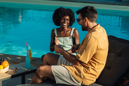 Happy couple relaxing by the pool, enjoying drinks and conversation