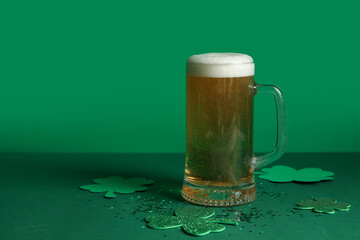 Glass of beer and clover on green background. St. Patrick's Day celebration