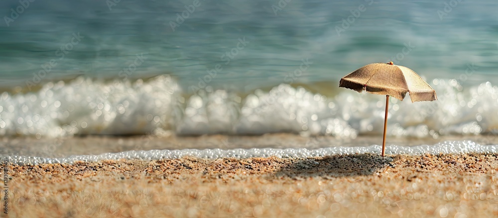 Fototapete minimalist beach scene featuring a small umbrella on golden sand with gentle waves in the background