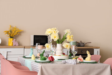Festive table setting with vase of flowers and Easter bunnies in modern kitchen