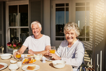 Elderly couple, portrait and smile with breakfast for anniversary date, retirement and bonding. Senior man, woman and outdoor with juice, fruit and brunch on home patio for relax and morning diet