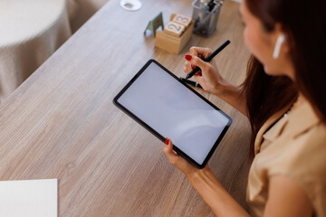 Mockup image of business woman sitting on the wooden table using stylus pen and digital tablet with...